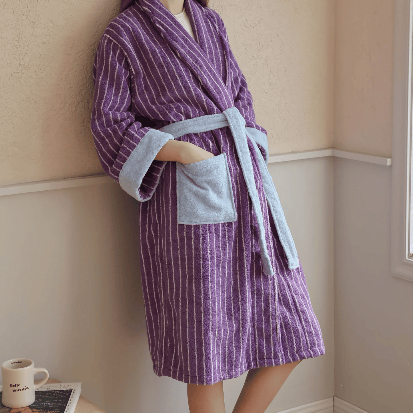 Person wearing a purple and gray striped robe in a room.