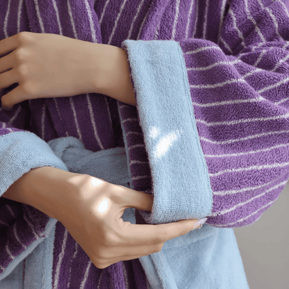 Person holding a light blue towel with a heart design against a purple striped background