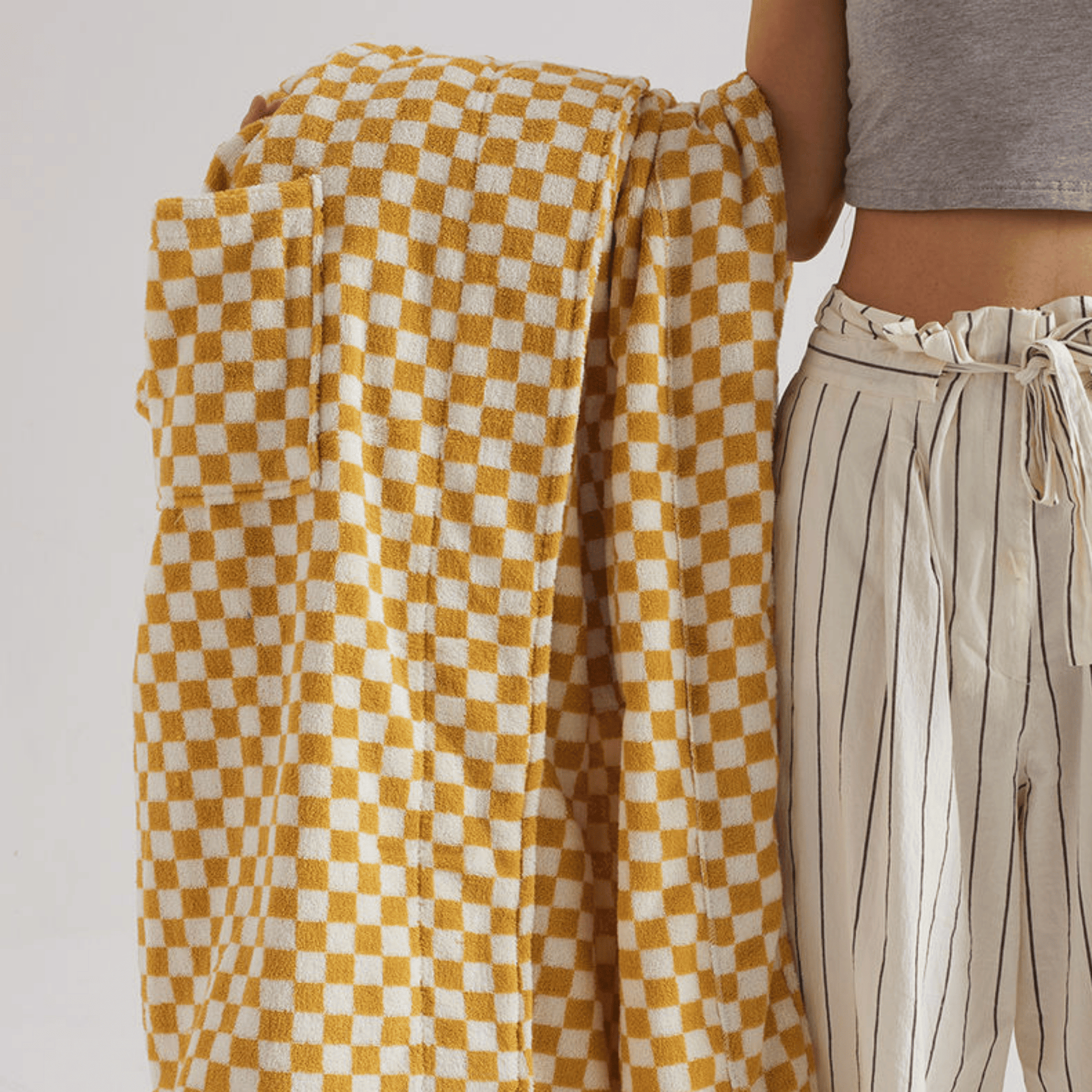 Person holding a yellow and white checkered towel with a neutral background