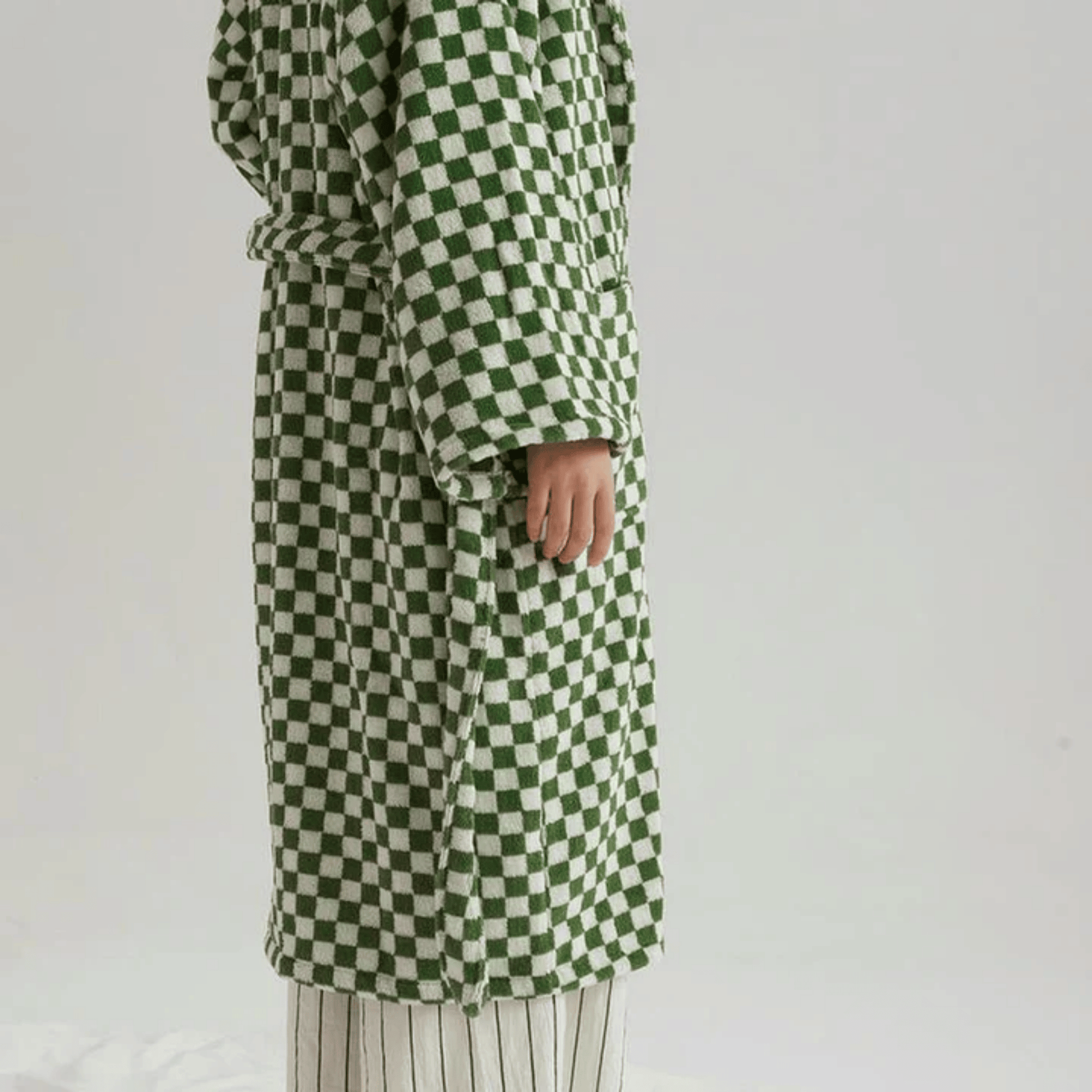 Green and white checkered coat worn by a person on a plain background