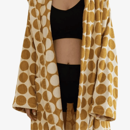 Person wearing a mustard yellow and white patterned robe over black clothing on a white background