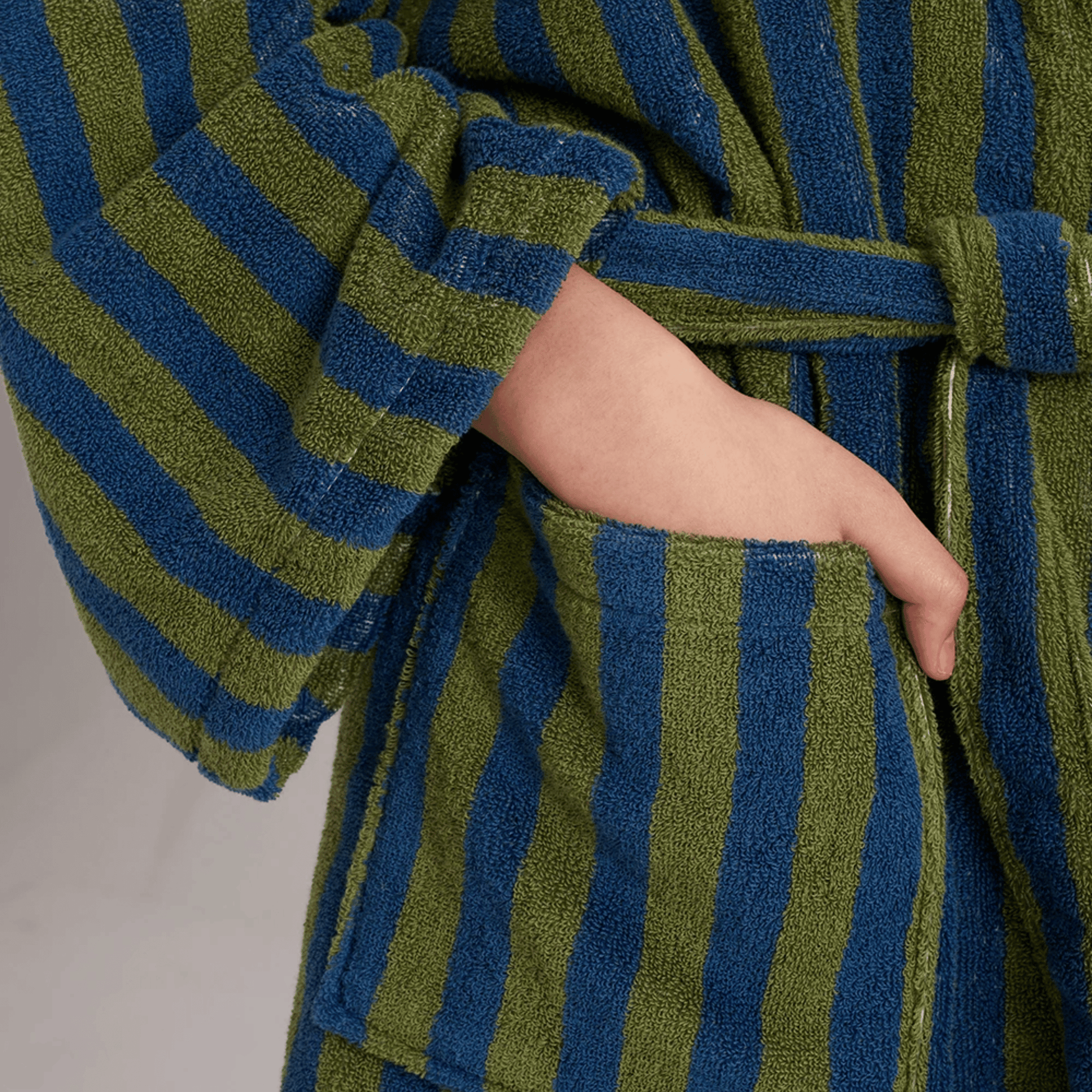 Green and blue striped robe with a belt on a neutral background