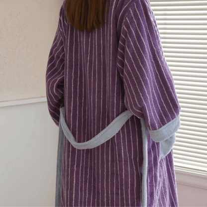 Person wearing a purple striped robe with gray trim indoors.