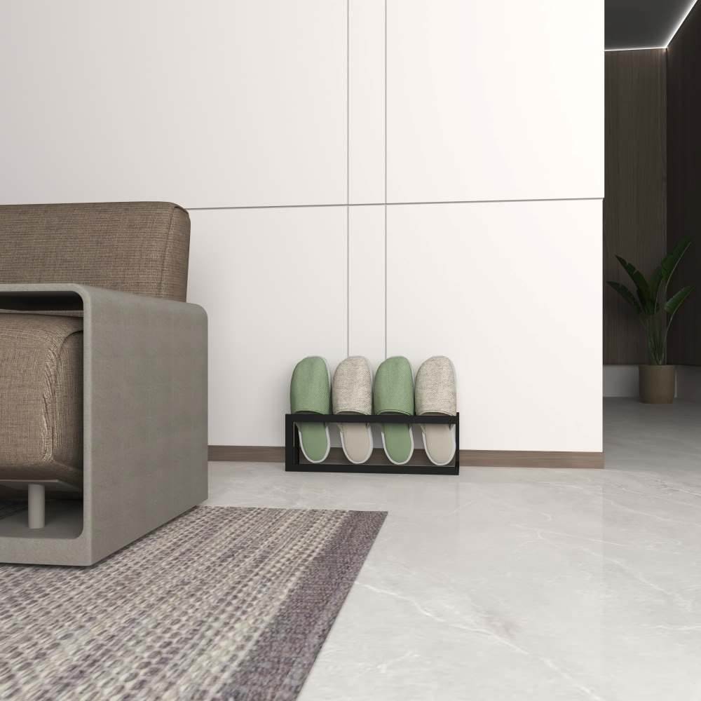 A black Metal Slippers and Shoe Rack neatly holding three pairs of slippers in a modern living room corner with minimalist decor.