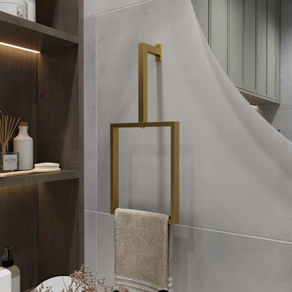 A minimalist gold-finished vertical towel ring is mounted on a light gray wall. The elegant rectangular design holds a beige towel, adding a luxurious touch to the bathroom decor.