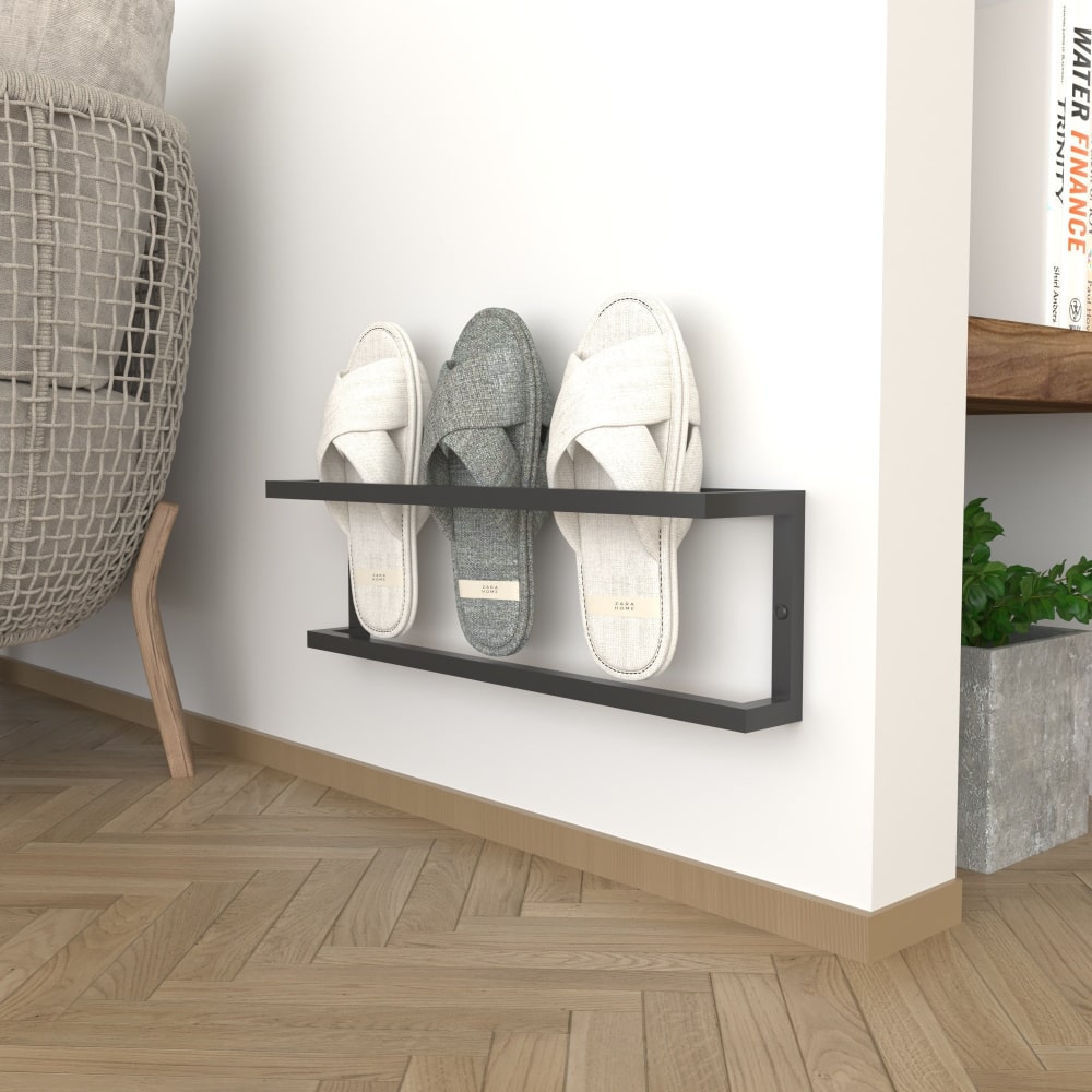 A minimalist black wall-mounted slipper rack on a plain background, holding three pairs of slippers, shown for small spaces with a focus on functionality and style.