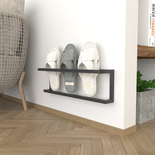 A minimalist black wall-mounted slipper rack on a plain background, holding three pairs of slippers, shown for small spaces with a focus on functionality and style.