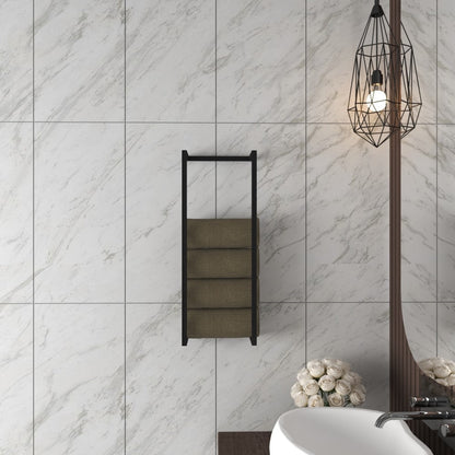 Modern wall-mounted towel and blanket storage rack in black, holding rolled towels, displayed in a minimalist bathroom setting with white marble walls and an industrial-style pendant light.