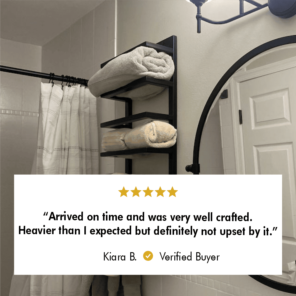 Wall-mounted black metal towel rack in a modern bathroom, holding neatly rolled towels with a round mirror and a shower curtain in the background.