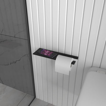 A black multifunctional bathroom shelf with a built-in toilet paper holder mounted on a marble-patterned wall, showing the in-use roll on the lower bar and the upper shelf for accessories.