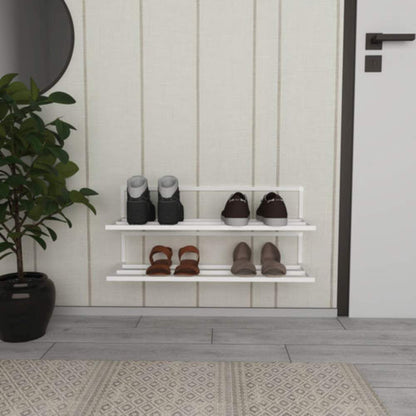 A white wall-mounted shoe rack with two tiers holding boots, sneakers, and heels, placed in an entryway with a potted plant, a circular mirror, and a beige paneled wall.
